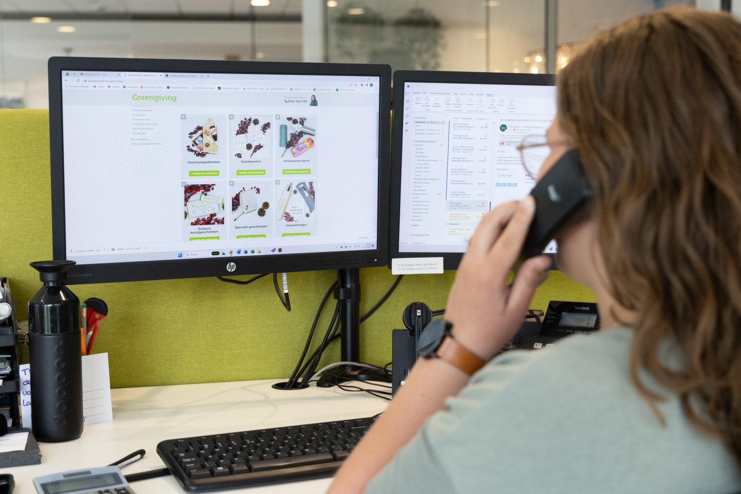 Greengiving employee on the phone at a desk with the promotional gifts webshop on screen